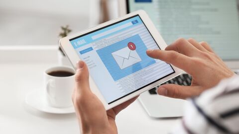 Zwei Hände halten ein Tablet, auf welchem eine E-Mail eingegangen ist 