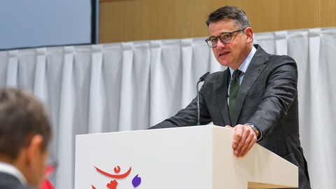 Mann steht an Rednerpult.