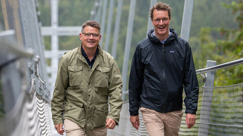 Hessens Ministerpräsident Boris Rhein (links) und Nordrhein-Westfalens Ministerpräsident Hendrik Wüst (rechts) in der Nähe von Willingen auf der längsten Hängebrücke Deutschlands, dem „Skywalk“, auf die Kamera zulaufend