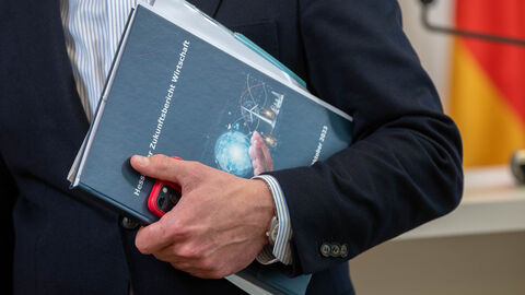 Hessischer Zukunftsbericht Wirtschaft wird ausgedruckt in einem Arm getragen