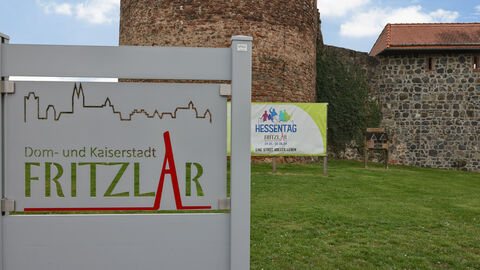 Das Bild zeigt ein Schild mit dem Schriftzug Fritzlar im Vordergrund sowie ein weiteres Schild mit dem Schriftzug Hessentag 2024 im Hintergrund