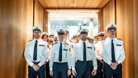 Mehrere Personen in Uniform stehen in einer Reihe. 