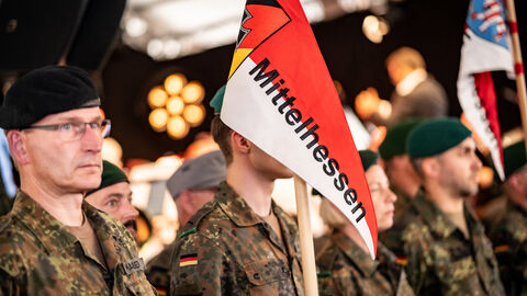 Mehrere Personen in einer Uniform halten eine rotweiße Fahne mit dem Schriftzug Mittelhessen hoch.