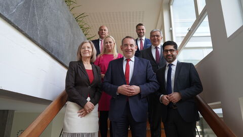 Mehrere Personen stehen auf Treppe und lachen in Kamera.