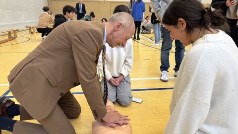 Bildungsminister Armin Schwarz übt in einer Schulturnhalle das Wiederbeleben an einer Erste-Hilfe-Puppe